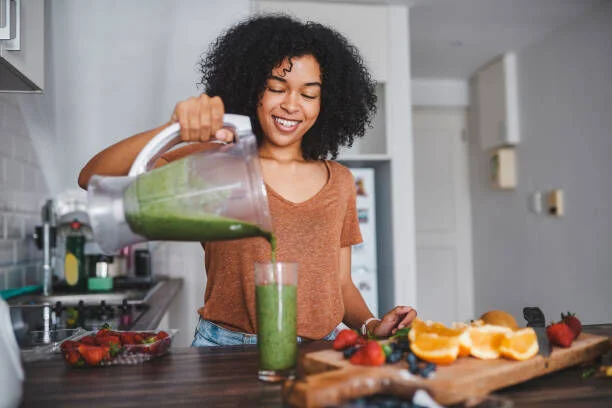 Guide des Meilleurs Blenders pour Smoothies - Guides d'achat et Idées Cadeaux pour toute la famille Femme qui réalise un smoothie vert avec un blender à la maison