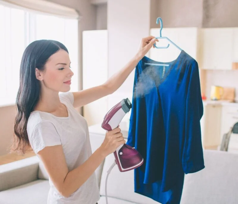 Guide des meilleurs Défroisseurs Vapeur Verticaux à Main - Guides d'achat et Idées Cadeaux pour toute la famille Femme qui utilise un défroisseur vapeur vertical