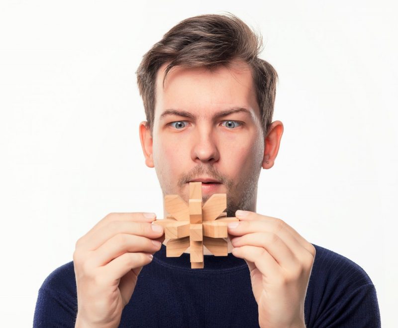 Homme qui essaye de résoudre un casse tête en bois